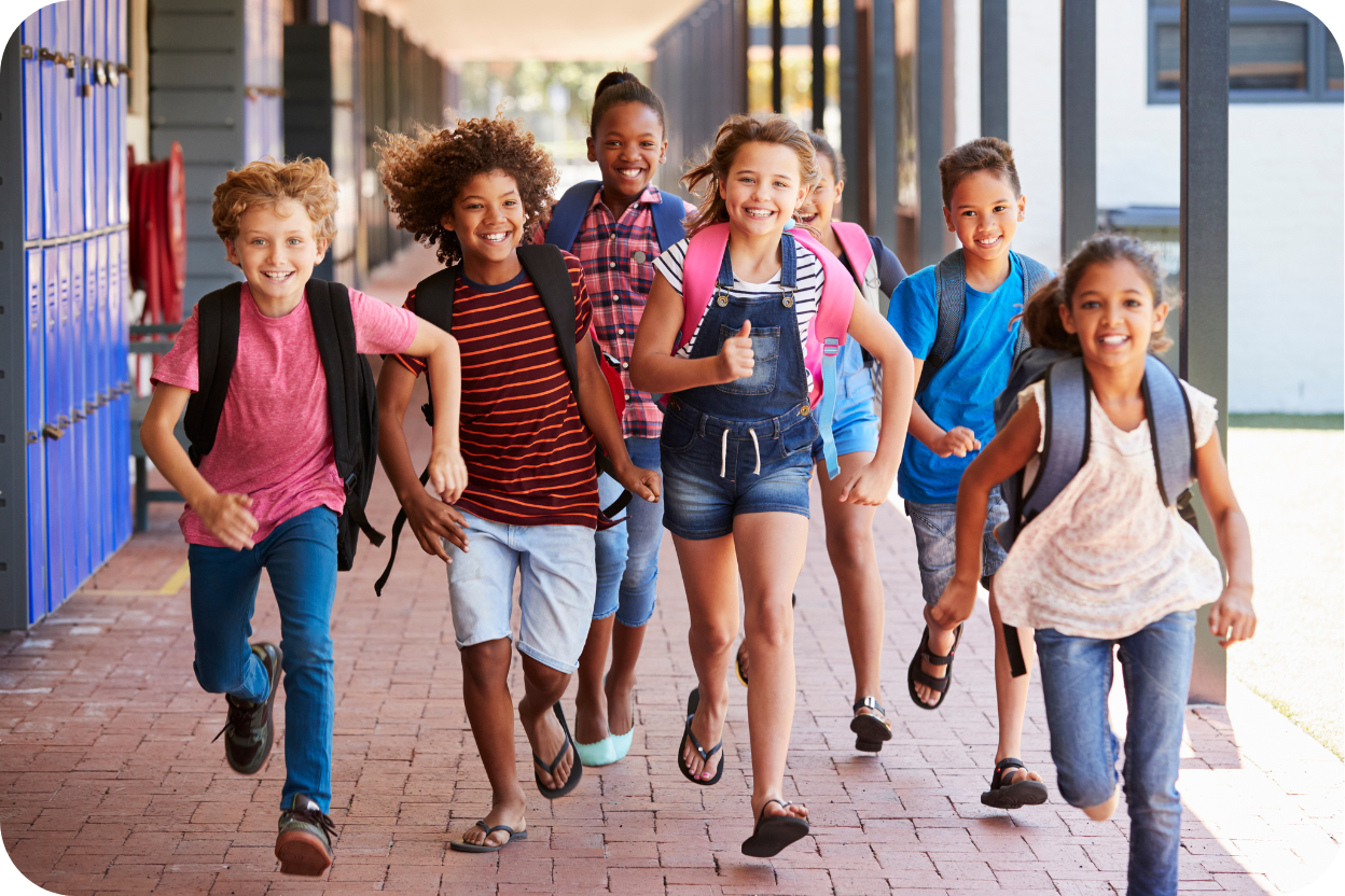 Grupo de sete crianças felizes (meninos e meninas de diferentes etnias e idades) correndo e sorrindo em um corredor de escola ao ar livre, usando mochilas, sugerindo o início das férias escolares.